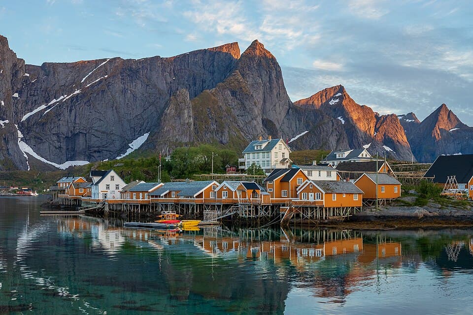 Yellow rorbu cabins on Sakrisøy beneath Navaren peak over Reinefjorden, Lofoten